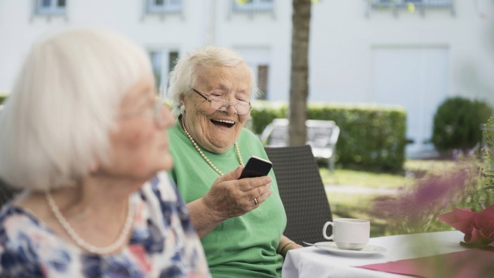 Senior woman laughing and using smartphone Bavaria Germany mit_2017_10199