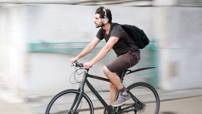 A view of a cyclist riding a bike in Hyde Park Corner while wearing headphones in London UK Photo