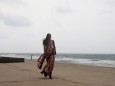 Eine Frau geht in Colombo auf Sri Lanka am Meer entlang.