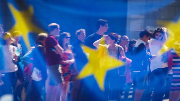 Prantls Blick: Brüssel: Menschen spiegeln sich in einem Fenster mit einer europäischen Flagge im Europäischen Parlament.