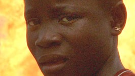 Ölkonzern in Nigeria: Ein nigerianisches Mädchen steht vor einer Flamme, mit der Gas abgefackelt wird. Shell zahlt jetzt eine Entschädigung an einige der Opfer von Menschenrechtsverletzungen im ölreichen Niger-Delta.