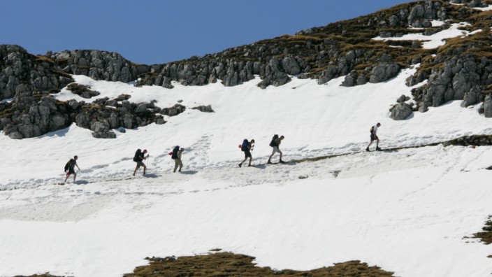 Wanderer queren im Karwendel ein Schneefeld.