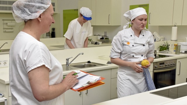 Azubi-Wettbewerb: Prüferin Sonja Hochmann (links) beobachtet Katharina Beil beim Kochen. Hinten bereitet Tabea Sackmann ihre Baguettes vor