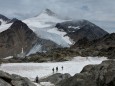 Wanderer queren in den Alpen ein Schneefeld.