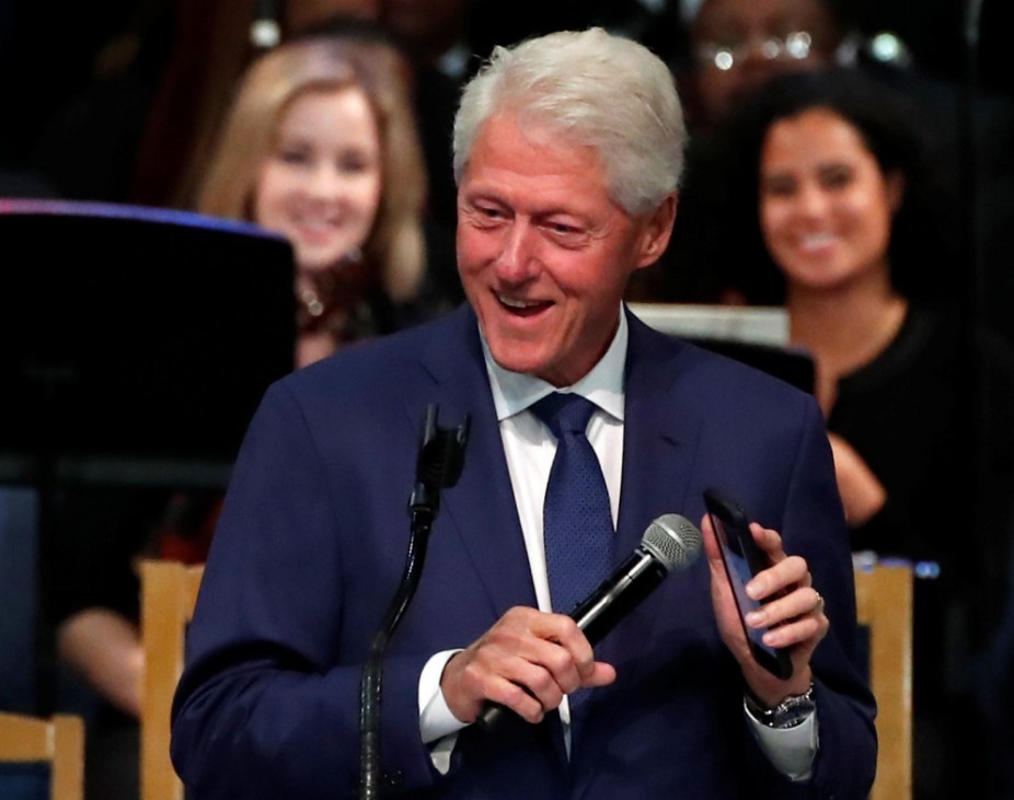 Former U.S. President Bill Clinton plays Aretha Franklin music on his mobile phone while speaking at the funeral service for the late singer at the Greater Grace Temple in Detroit
