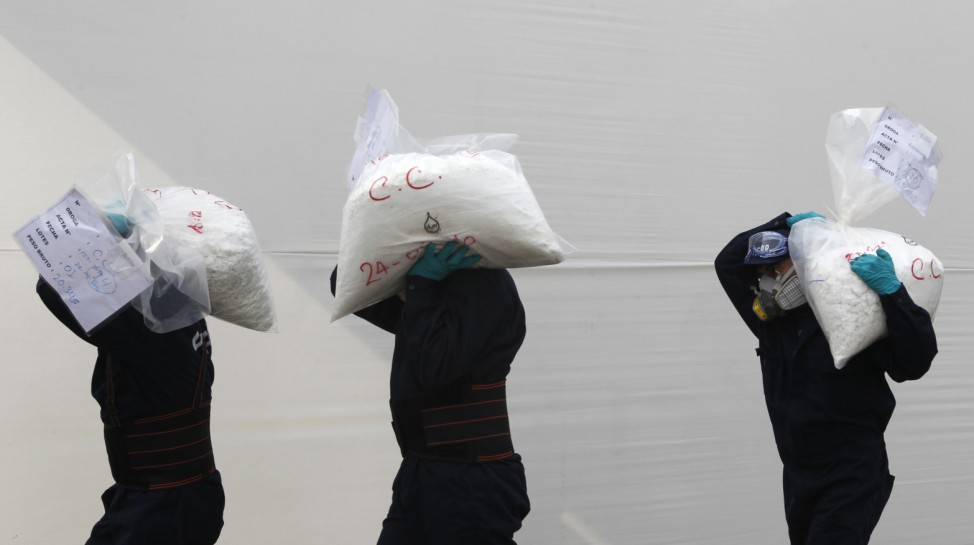 Anti-narcotics workers carry bags containing cocaine to an incinerator in Lima