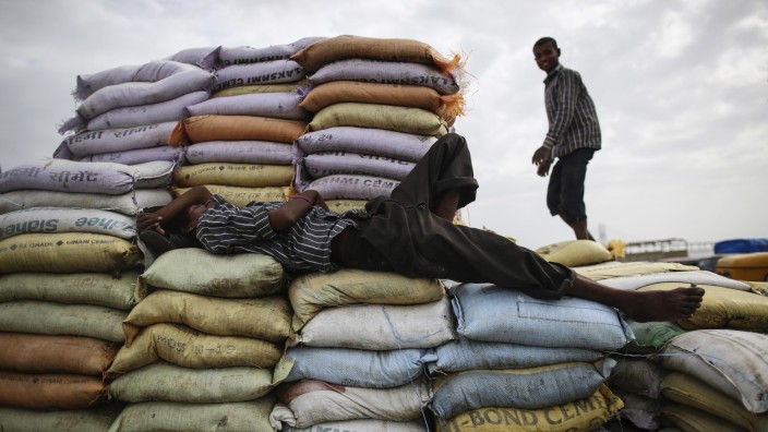 A labourer sleeps on sacks of sand as another works at a market in Mumbai