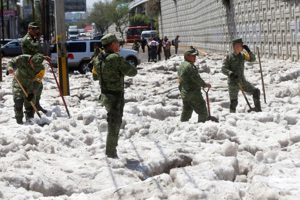 Soldiers try to clear away ice after a heavy storm of rain and hail which affected some areas of the city in âÄ'âÄ'Guadalajara