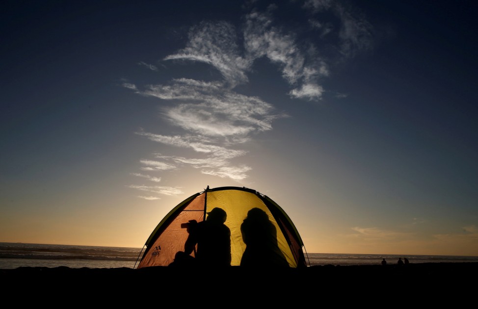 A man take a picture inside of his tent during the sunset in a beach at La Serena