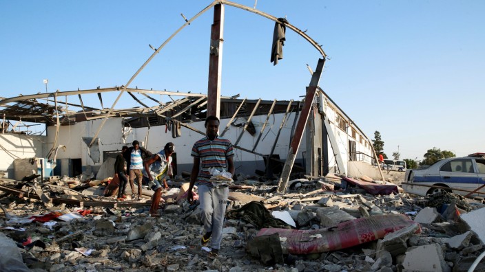 Migrants carry the remains of their belongings from among rubble at a detention centre for mainly African migrants that was hit by an airstrike in the Tajoura suburb of the Libyan capital of Tripoli