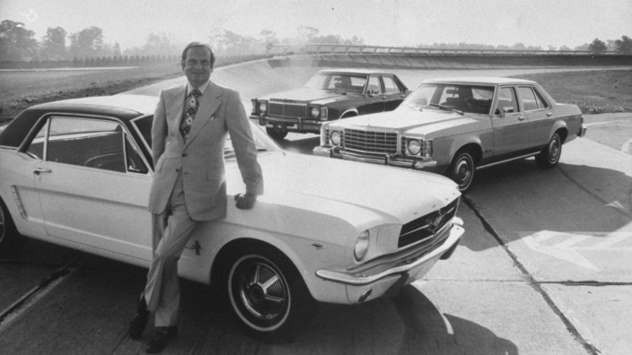Ford Motor Co President Lee A Iacocca leaning against a F