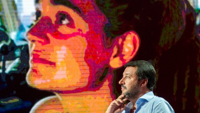 Matteo Salvini spricht vor einer Monitorwand, die Carola Rackete zeigt