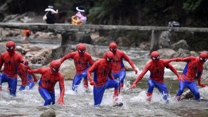Participants dressed in Spiderman cosplay costumes run in a creek during an event at the Jiujiang National Forest Park in Chenzhou