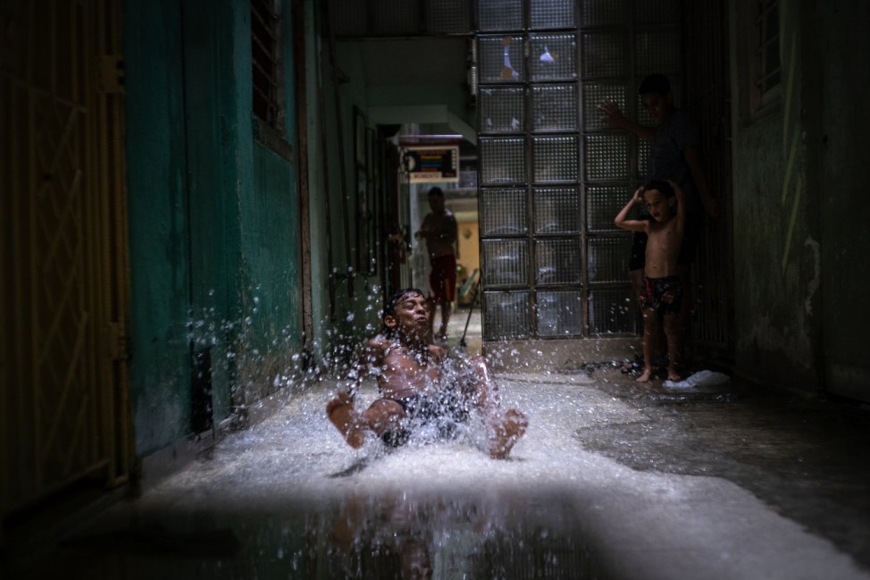 Wasserspiel: Eine Pfütze wird für dieses Kind in Havanna, Kuba, zur Rutschbahn.