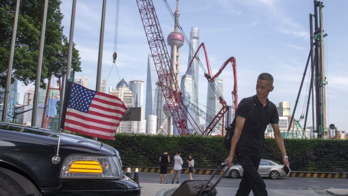 Handelsstreit mit China: Ein Reisender läuft in Shanghai an einem Auto der US-Botschaft vorbei.