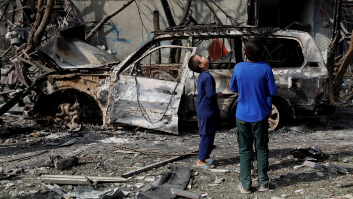 Afghan boys look the site of Sunday's attack in Kabul, Afghanistan