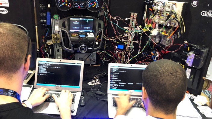 Attendees of the 2019 DEF CON cybersecurity event are seen at the conference's car hacking village in Las Vegas