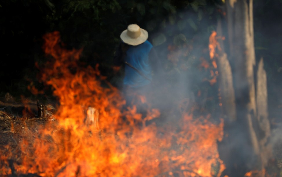 A man works in a burning tract of Amazon jungle as it is being cleared by loggers and farmers in Iranduba