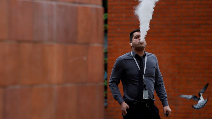 FILE PHOTO: A man vapes outside an office block in Manchester, Britain