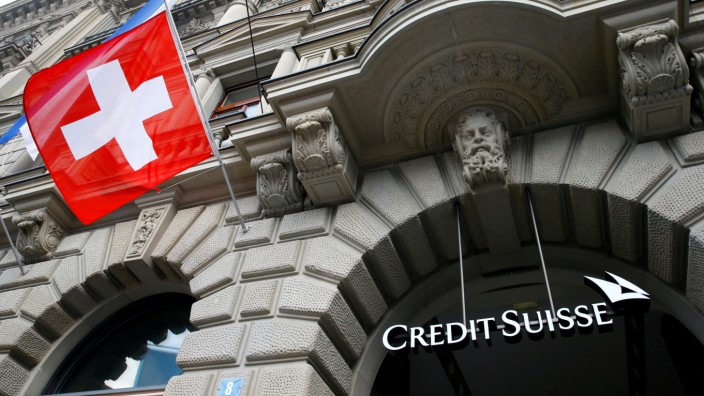 FILE PHOTO: Switzerland's national flag flies below a logo of Swiss bank Credit Suisse in Zurich
