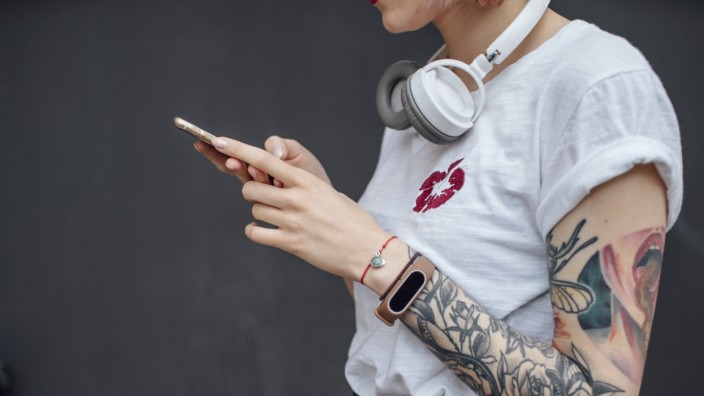 Close up of tattooed young woman with headphones using cell phone model released Symbolfoto PUBLICA