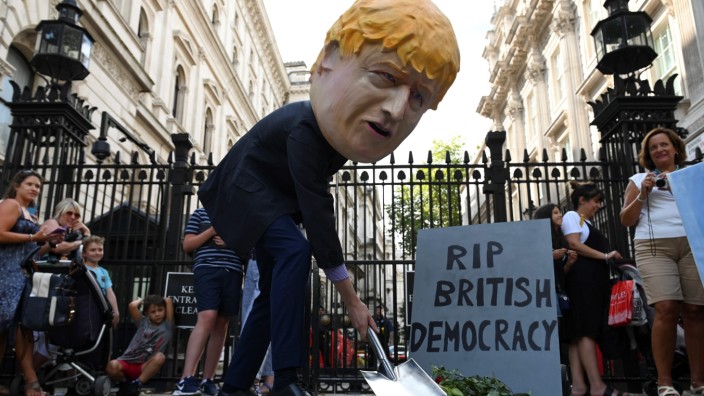 Liberale Demokratie: Symbolische Bauarbeiten im Mutterland der Demokratie: Ein Mensch mit Maske von Premierminister Boris Johnson schaufelt im August 2019 in London ein Grab für den Parlamentarismus.