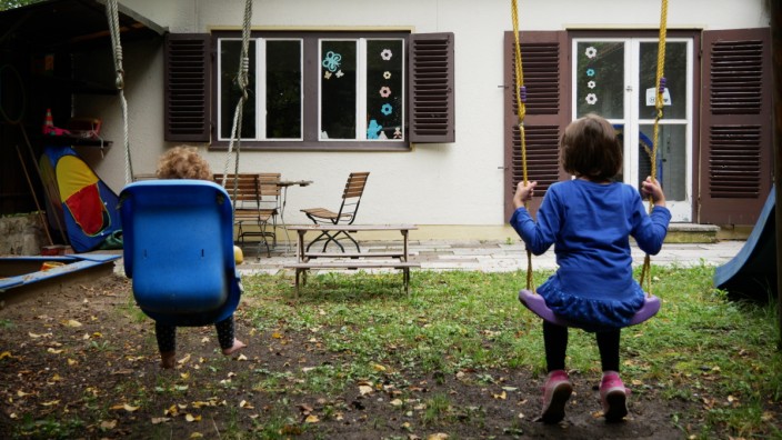 Familien in Bayern: Mia und Anna schaukeln auf dem Spielplatz von Haus Felix. Das Haus gegenüber wird zum Spielen und für gemeinsame Feste genutzt.