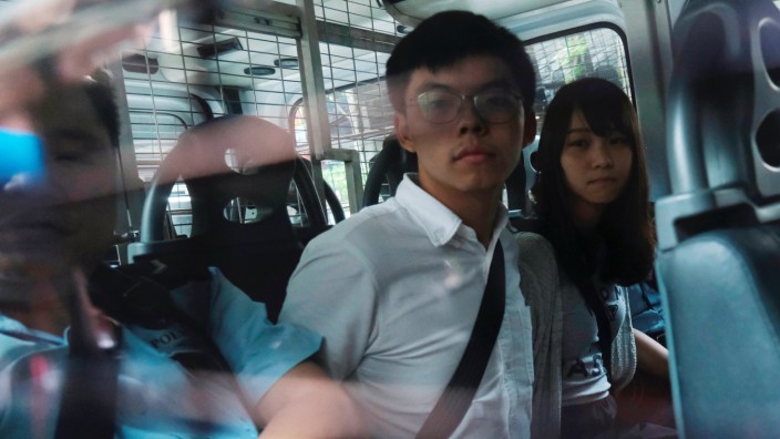Pro-democracy activists Joshua Wong and Agnes Chow arrive at the Eastern Court by police van after being arrested on suspicion for organising illegal protests, in Hong Kong