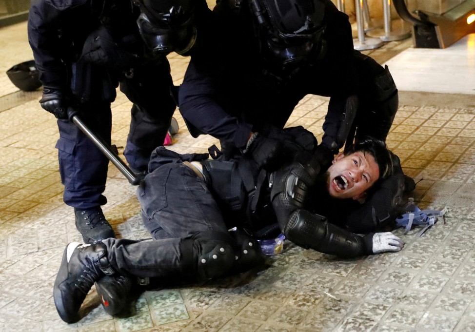 A demonstrator is detained by police officers during a protest in Hong Kong