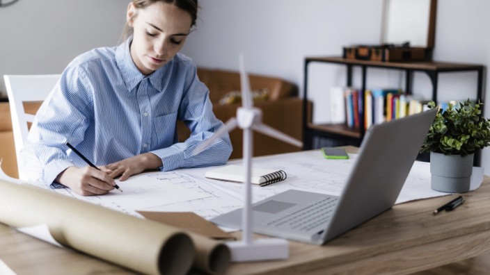 Woman in office working on plan with wind turbine model on table model released Symbolfoto property