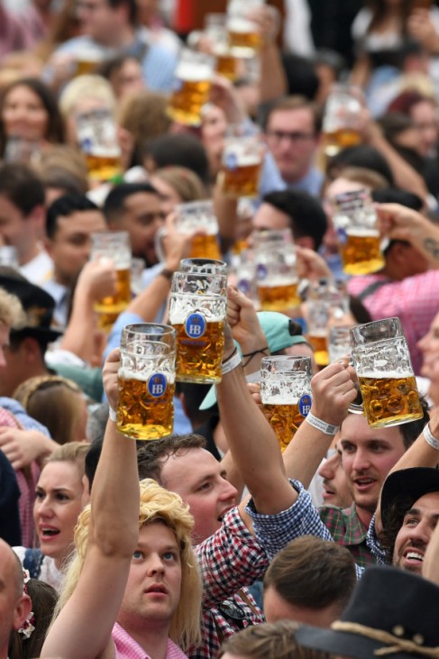 Besucher auf dem Oktoberfest 2019 in München trinken Bier aus Masskrügen.