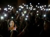 People hold up photos of assassinated anti-corruption journalist Daphne Caruana Galizia and torches on mobile phones during a vigil to mark eleven months since her murder in a car bomb, in Valletta