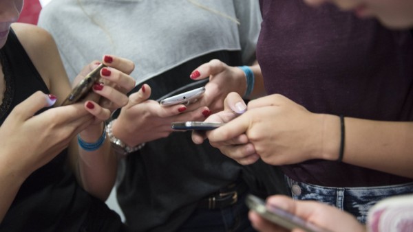 Mädchen tippen in Berlin auf ihren Handys Smartphones