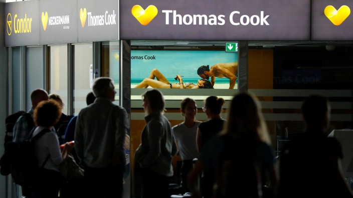 Passengers are silhouetted in front of a closed service counter of travel agent Thomas Cook and airline Condor at the airport  in Frankfurt