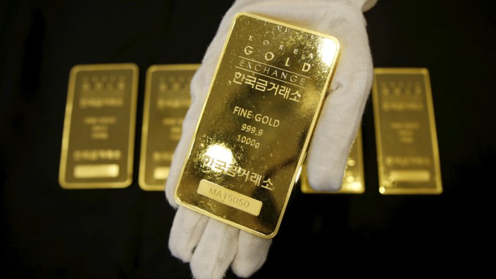 An employee poses for photographs with a one kilogram gold bar at the Korea Gold Exchange in Seoul