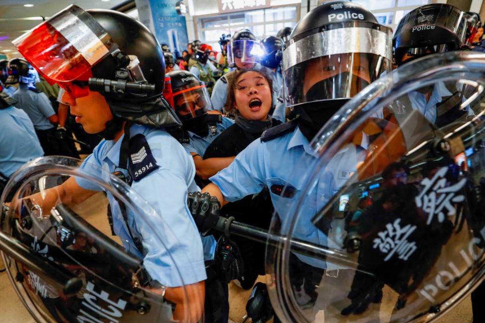 Riot police detain a woman as anti-government protesters gather at Sha Tin Mass Transit Railway (MTR) station to demonstrate against the railway operator, which they accuse of helping the government, in Hong Kong