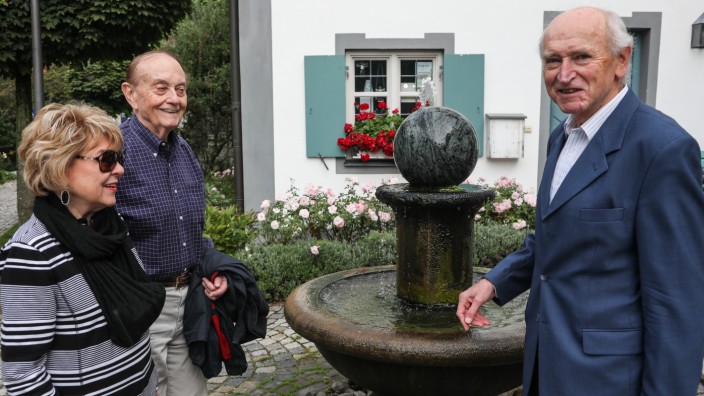 Familienforscher Anton Mayr und zwei Gäste stehen vor einem kleinen Brunnen.