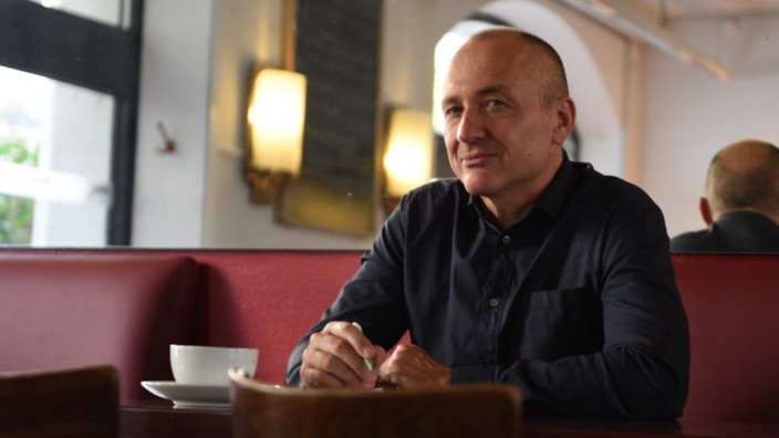 Rainer Jund war Arzt am Klinikum Großhadern und hat nun ein Buch geschrieben, er sitzt an einem Tisch im Cafe.