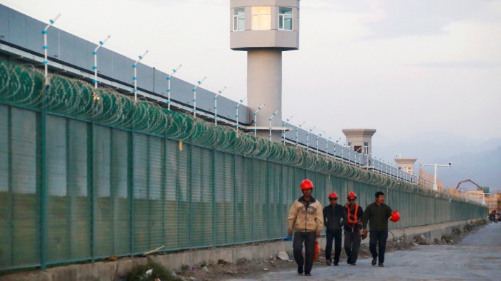 FILE PHOTO: Workers walk by the perimeter fence of what is officially known as a vocational skills education centre in Dabancheng