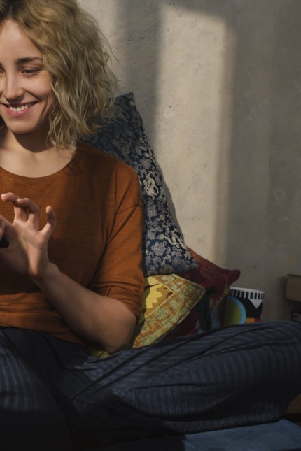 Portrait of smiling young woman sitting on bed using E book reader model released Symbolfoto propert