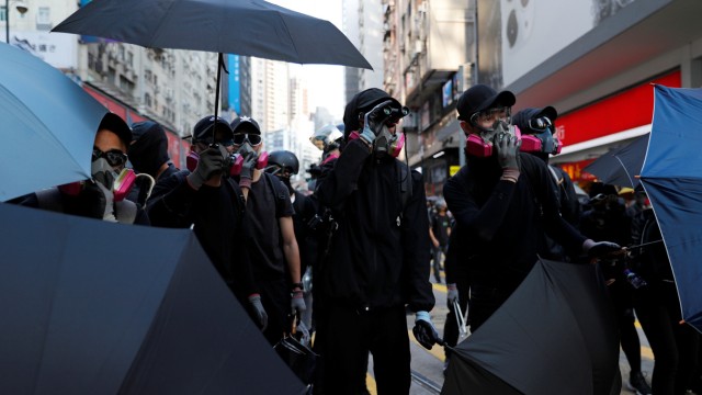 Anti-government protesters hold umbrella to take cover from tear gas during a march billed as a global 'emergency call' for autonomy, in Hong Kong