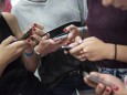 Mädchen tippen in Berlin auf ihren Handys Smartphones