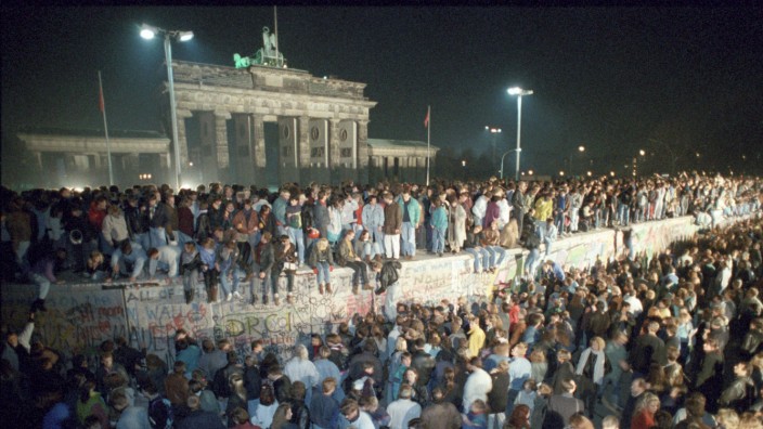 Deutsche Einheit: Menschen auf der Berliner Mauer vor dem Brandenburger Tor in der Nacht vom 9. auf den 10. November 1989.