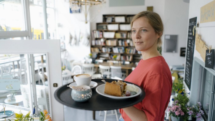 Young woman serving coffee and cake in a cafe model released Symbolfoto property released PUBLICATIO