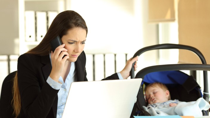 Stressed mother working taking care of her baby at office model released Symbolfoto PUBLICATIONxI