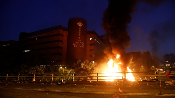 Protesters are seen next to a fire at Hong Kong Polytechnic University (PolyU) in Hong Kong
