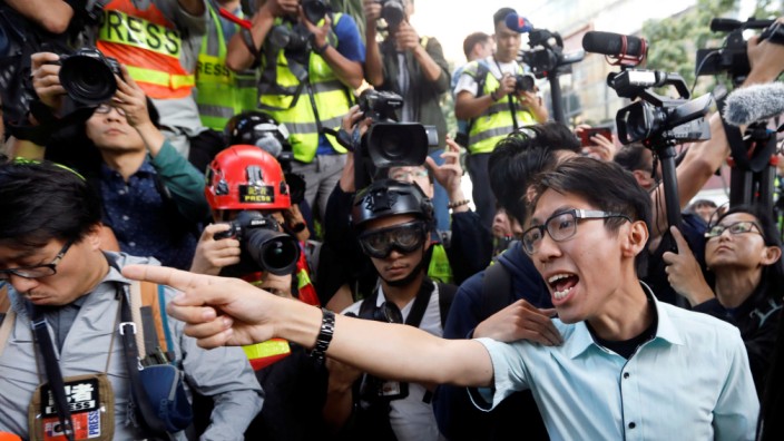 A pro-democratic winning candidate at district council local elections argues with police officers as they walk towards the campus of the Polytechnic University (PolyU) in Hong Kong