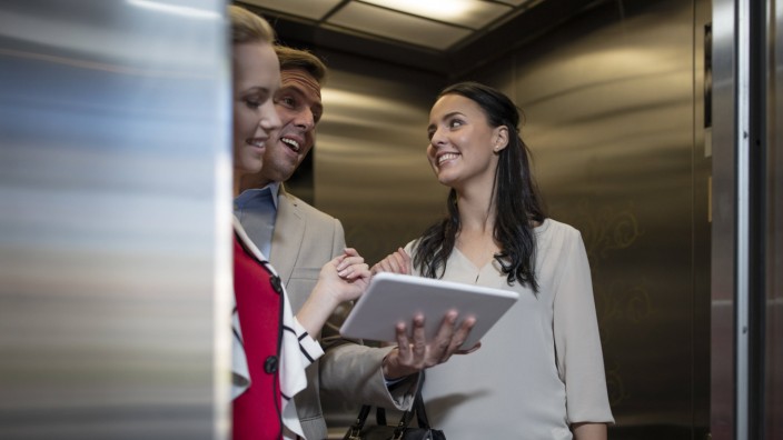 Business people in elevator with tablet talking model released Symbolfoto property released PUBLICAT