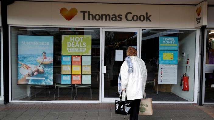 FILE PHOTO: A woman stands outside a closed Thomas Cook travel agents store near Manchester, Britain