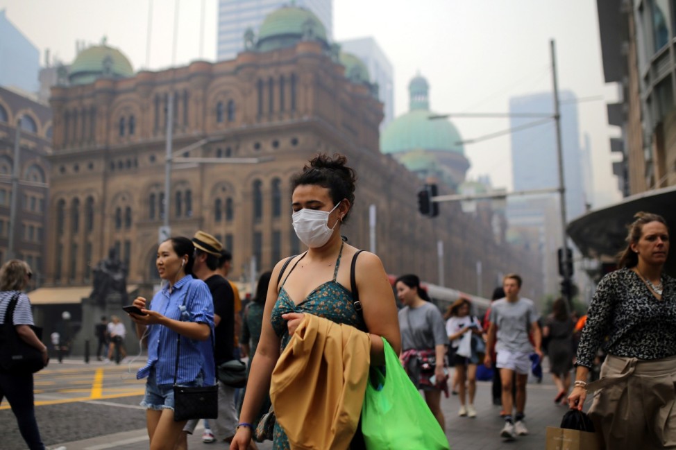Pedestrians are seen wearing masks as smoke haze from bushfires in New South Wales blankets the CBD in Sydney